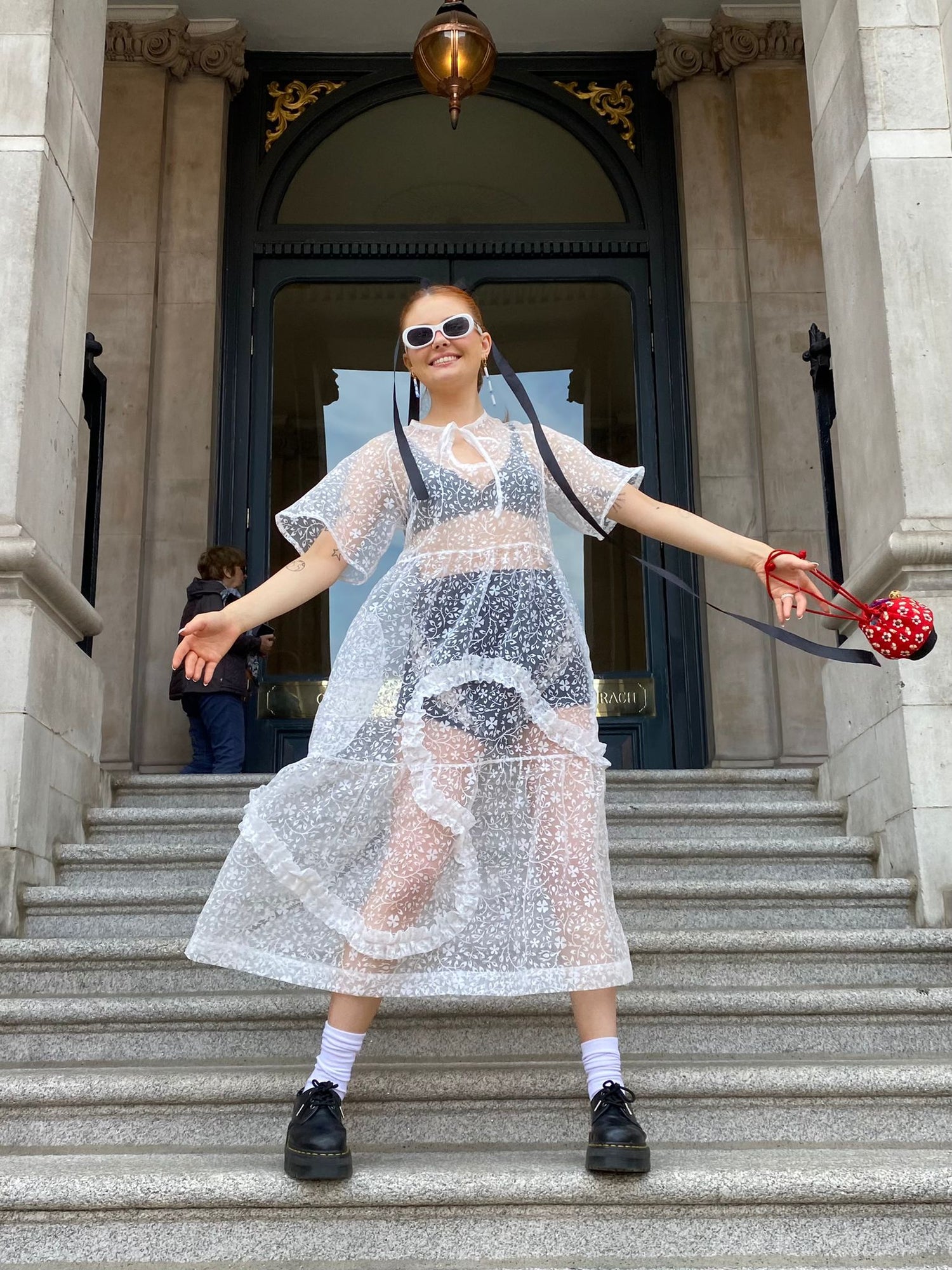 model wears sheer floral dress upcycled form a curtain, featuring an asymmetrical ruffle and pockets, made by jen Byrne