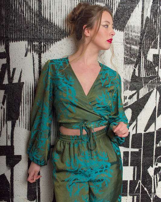 Woman wearing a green and blue patterned outfit against a black and white abstract wall.
