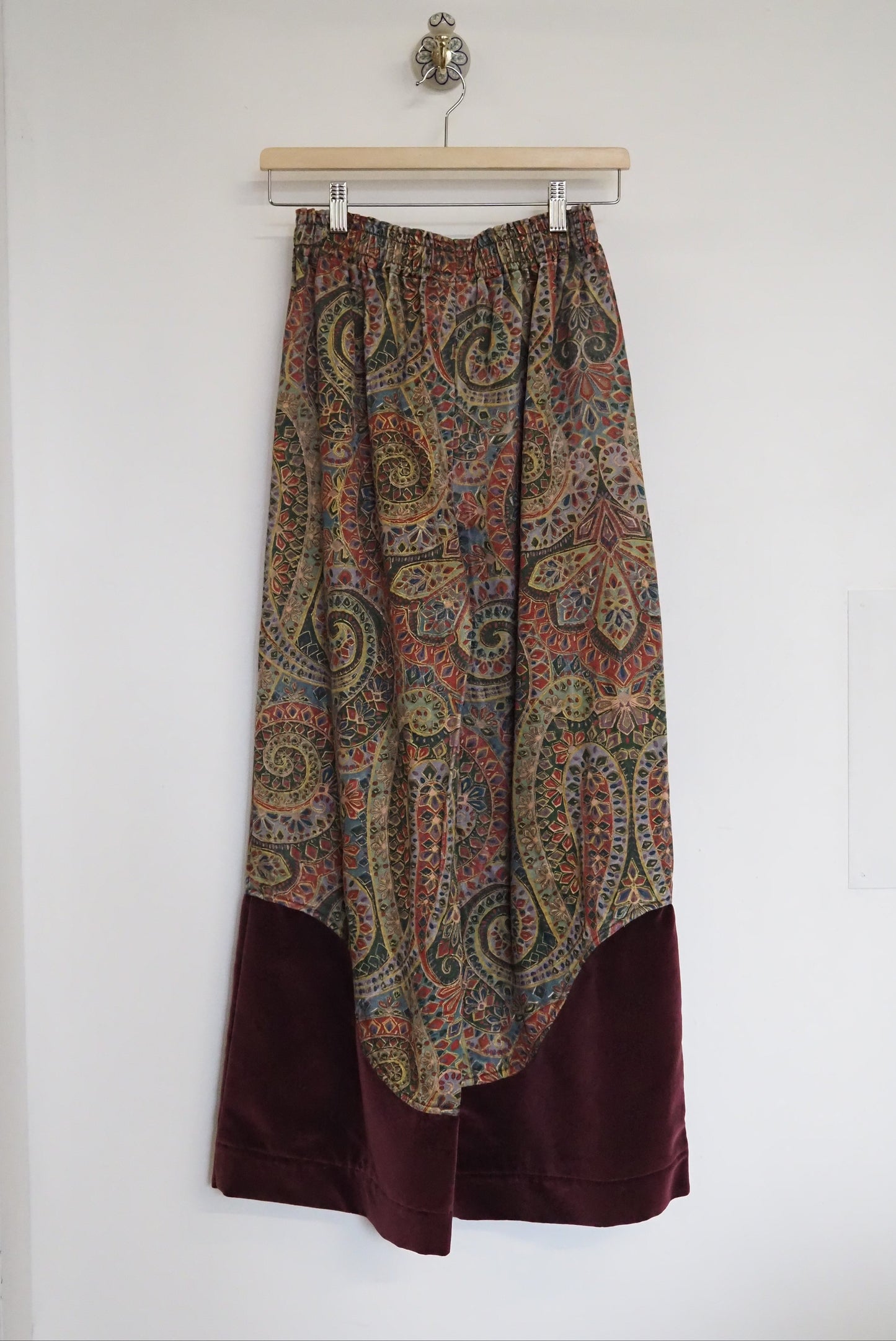 Paisley patterned skirt on a hanger against a white wall